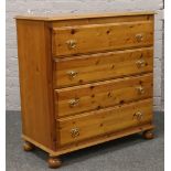 A modern pine chest of four drawers raised on bun feet.