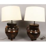 A pair of salt glazed pottery table lamps moulded with animal mask handles with cream shades.