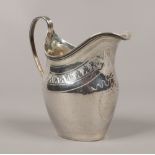 A George III silver cream jug with bright cut engraving and reeded decoration to the rim and handle,