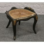 A Victorian ebonised stool with bergere seat and with gilt and mother of pearl decoration, raised on