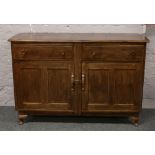 An Ercol style carved and paneled oak sideboard, raised on squat cabriole supports