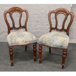 A pair of Victorian mahogany balloon back chairs with upholstered seats and raised on turned and