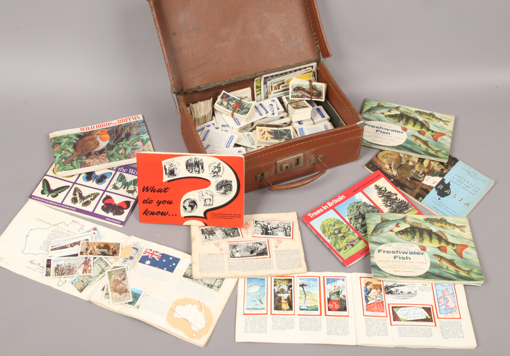 A small suitcase and contents of tea cards loose and in albums, along with a framed P.G chimp