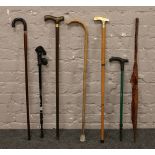 A bundle of walking sticks including a brass handle example, along with an early to mid 20th century