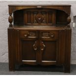 A mid 20th century oak court cupboard with carved decoration and panelled doors.