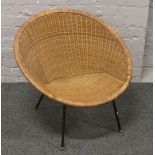 A vintage basketware 1960s chair raised on painted steel legs.