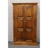 A carved and panelled pine wardrobe.