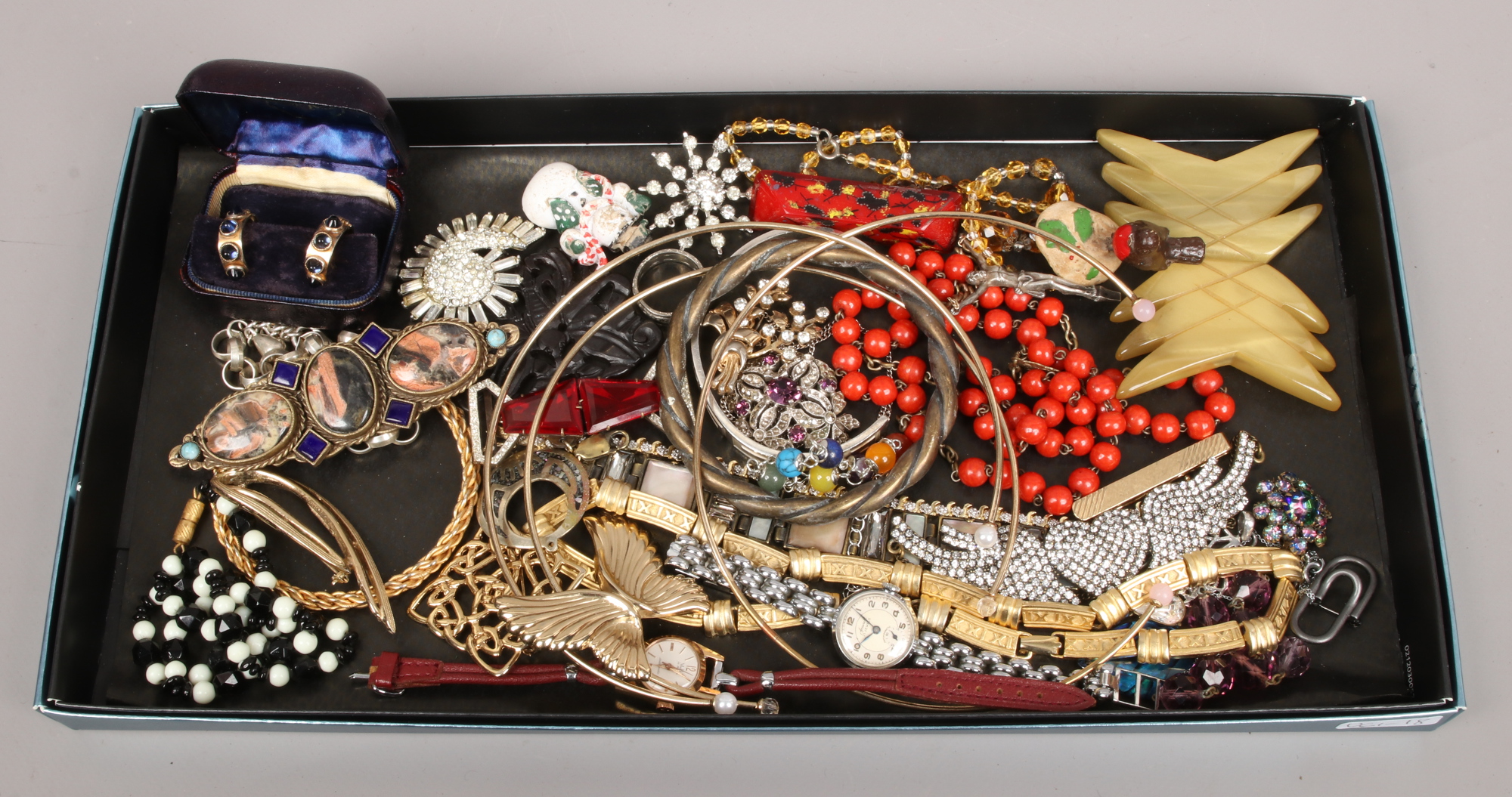 A tray of costume jewellery including white paste set brooches, wristwatches, bangles, rosary