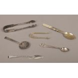 A collection of silver and white metal items to include silver spoon, silver claw sugar tongues,