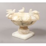 A small carved alabaster font surmounted with four doves, 12cm wide.