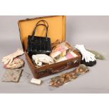A small vintage leather suitcase containing ladies evening gloves, purses and handbags etc.