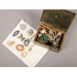 A tin of modern costume jewellery and a collection of brooches.