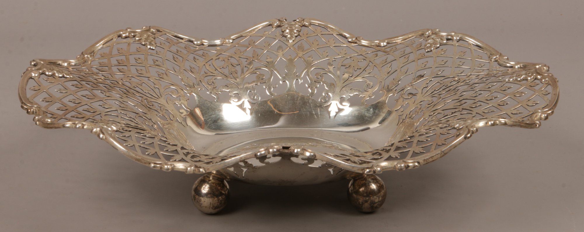 A silver pierced dish raised on four ball feet assayed Sheffield, partial hallmarks, total weight