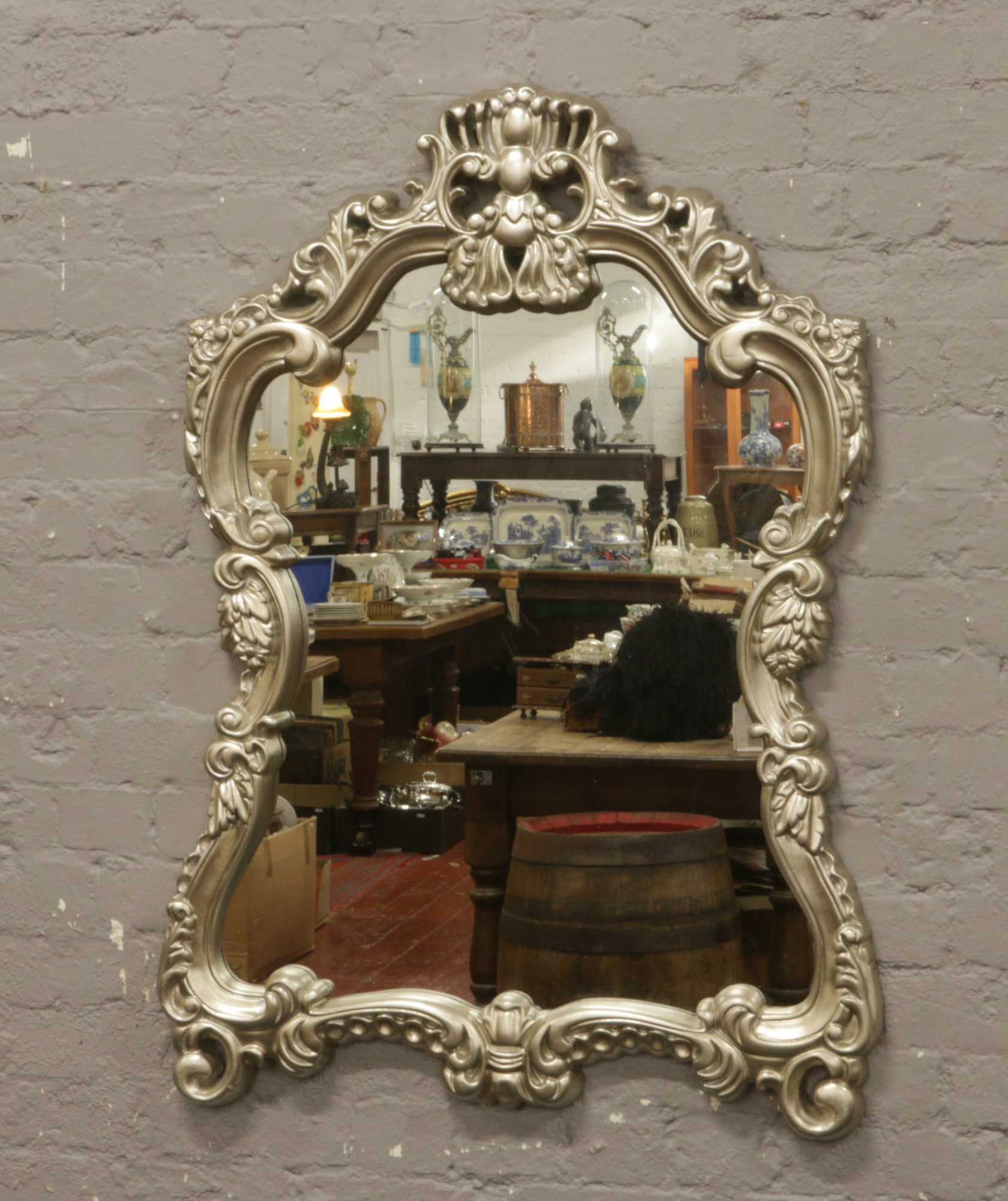 A large ornate silvered frame wall mirror, 116cm x 77cm.