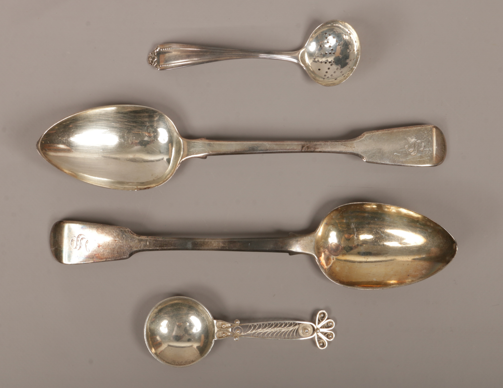 Two monogrammed Georgian silver table spoons assayed London 1825, along with a sifting spoon and