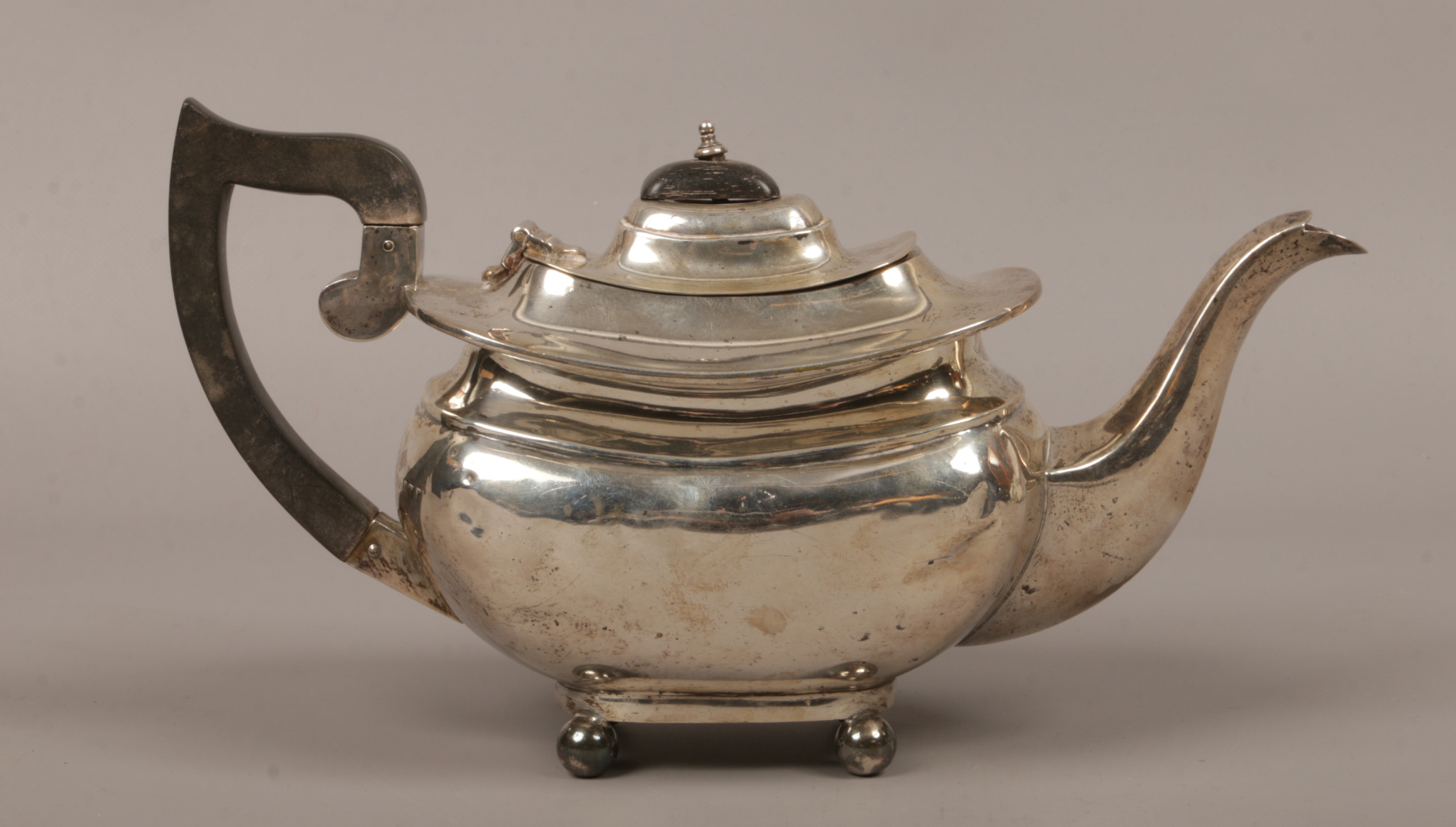 A George V silver teapot raised on four ball feet, assayed Birmingham 1916 by S. Blanckensee & Son