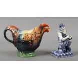 A Continental blue and white delft figure of a shoemaker and a novelty pottery Rooster teapot.