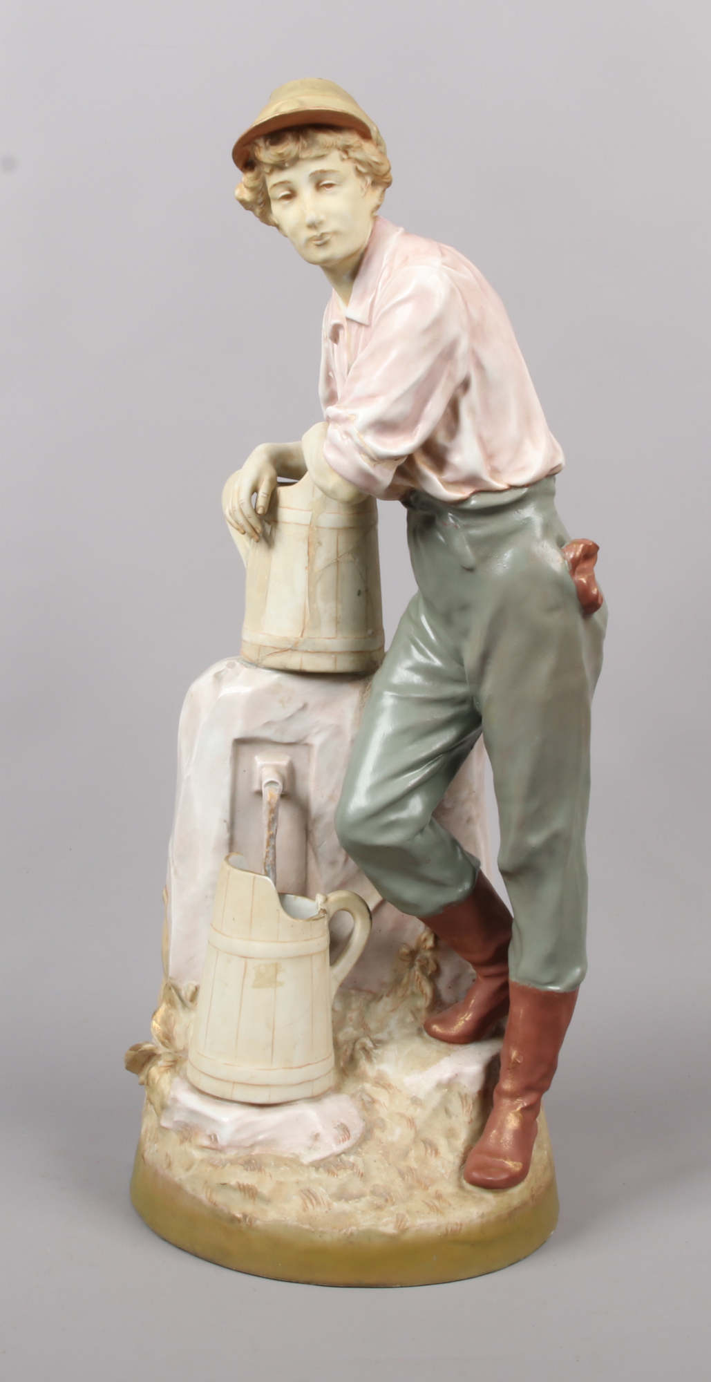 A large Royal Dux figure of a young farm worker collecting water. Decorated in pale hues. Pink