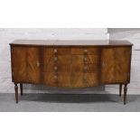 A mahogany bow front sideboard with lined cutlery drawer raised on reeded supports.