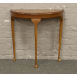 A yew wood veneered demi lune side table.