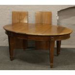 A George V carved mahogany oval extending dining table raised on tapering square legs, along with