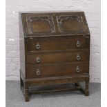 A carved oak bureau raised on turned supports.