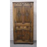 A carved oak floor standing corner cupboard with central drawer.