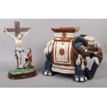 A decorative glazed pottery elephant stool along with a Juliana collection crucifix.