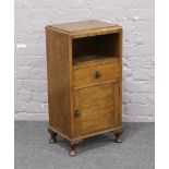 A 1930s carved oak and Bakelite bedside cabinet raised on squat cabriole legs.