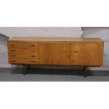 A large teak sideboard raised on tapering supports L 199cm x D 46cm x H 78cm.