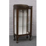 A carved oak single door display cabinet on ball and claw feet.