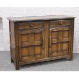 An Ercol carved and panelled dark oak sideboard. H 86cm L 121cm D 46.5cm.