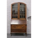 A carved oak dome top lead glazed bureau bookcase raised on cabriole legs.