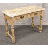 A stripped Victorian pine two drawer side table raised on turned supports.