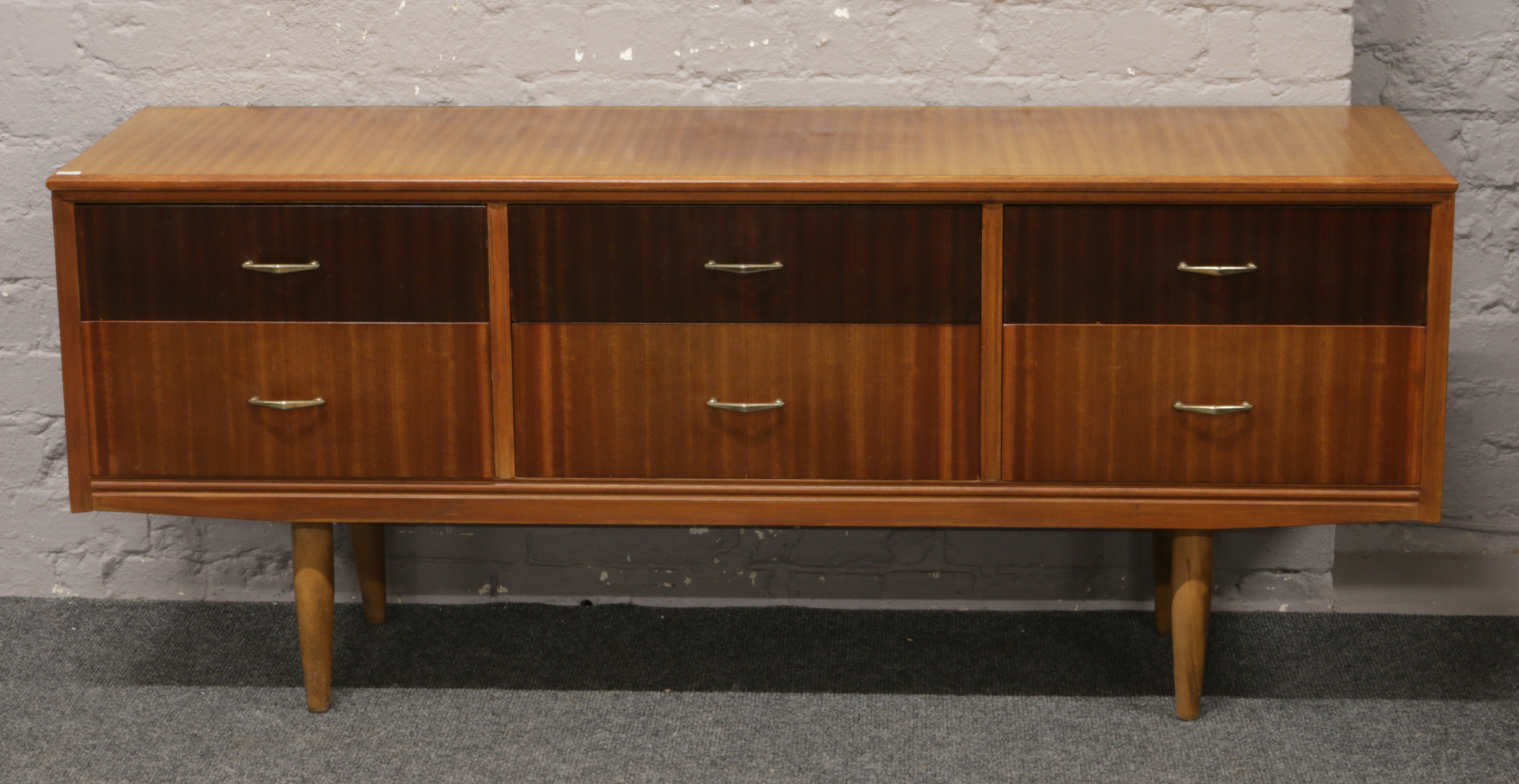 A two tone teak sideboard incorporating six drawers and raised on in-stepped supports, L 158.5cm x H