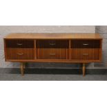 A two tone teak sideboard incorporating six drawers and raised on in-stepped supports, L 158.5cm x H