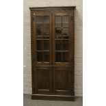 A carved oak glazed bookcase over cupboard base, H 168cm x W 82cm x D 29cm.