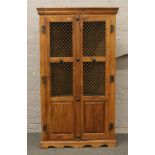 A carved hardwood Indonesian corner cupboard with iron mesh decoration.