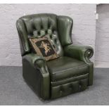 A green deep buttoned leather reclining wing arm chair with built in foot rest.