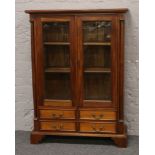 A mahogany glass front bookcase over four drawer base.