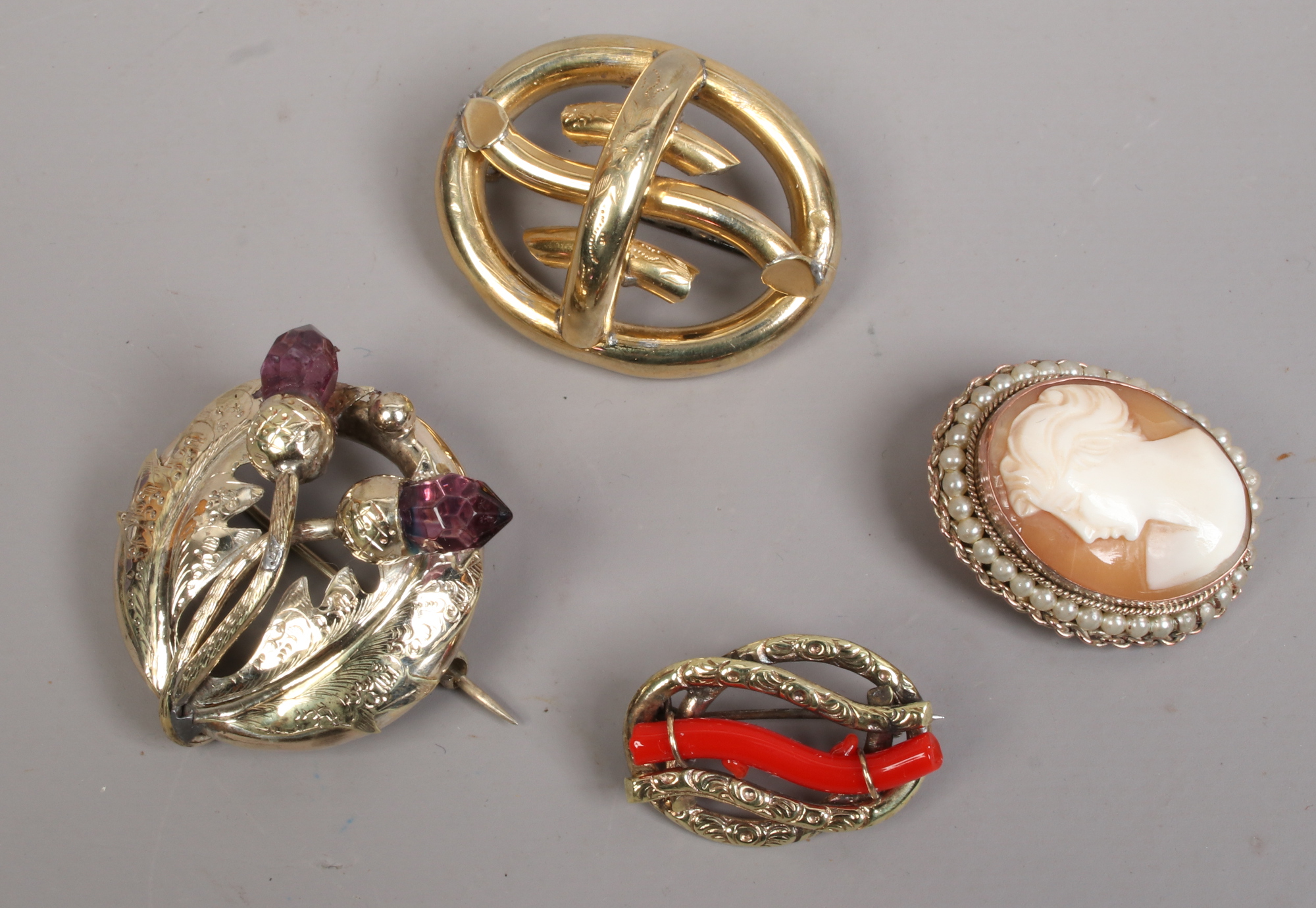 Four yellow metal brooches including a Scottish thistle and cameo examples.