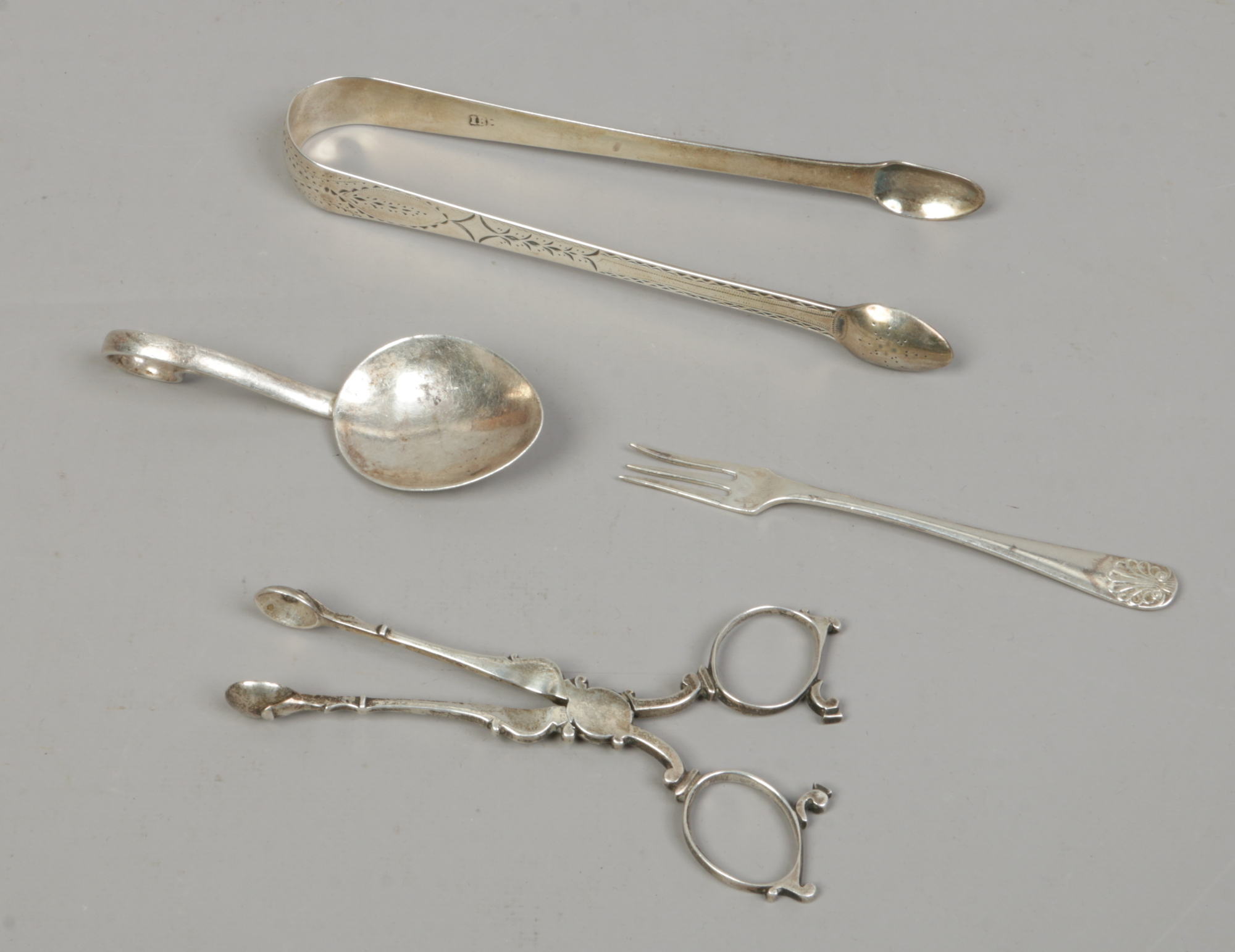 Four pieces of silver including a pair of Georgian sugar tongues, pickle fork, spoon etc, gross