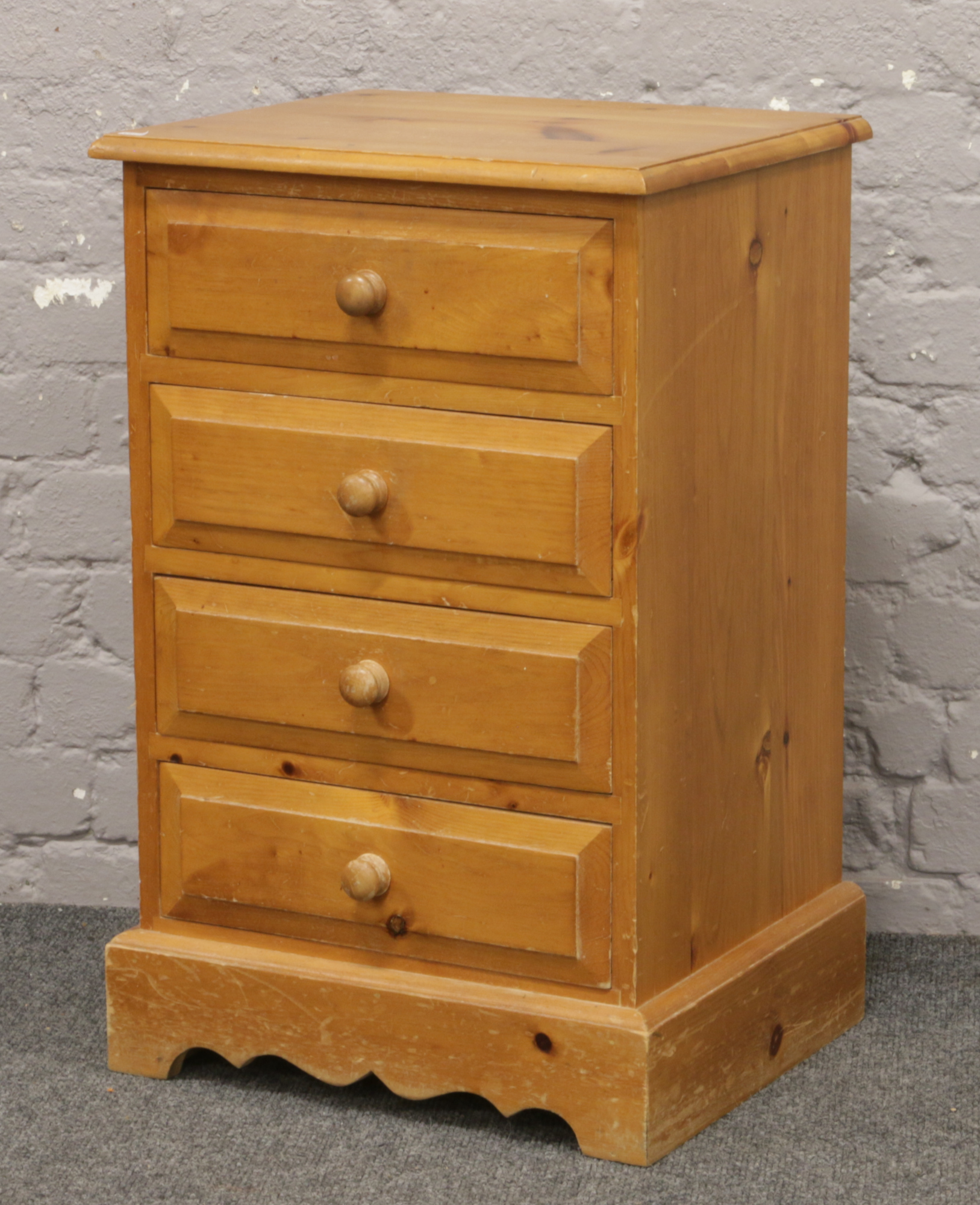 A pine bedside chest of four drawers.