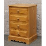 A pine bedside chest of four drawers.