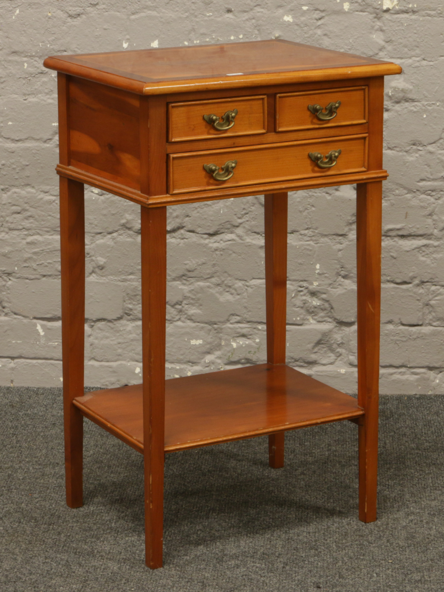 A two tone yew wood three drawer chest raised on square tapering legs.