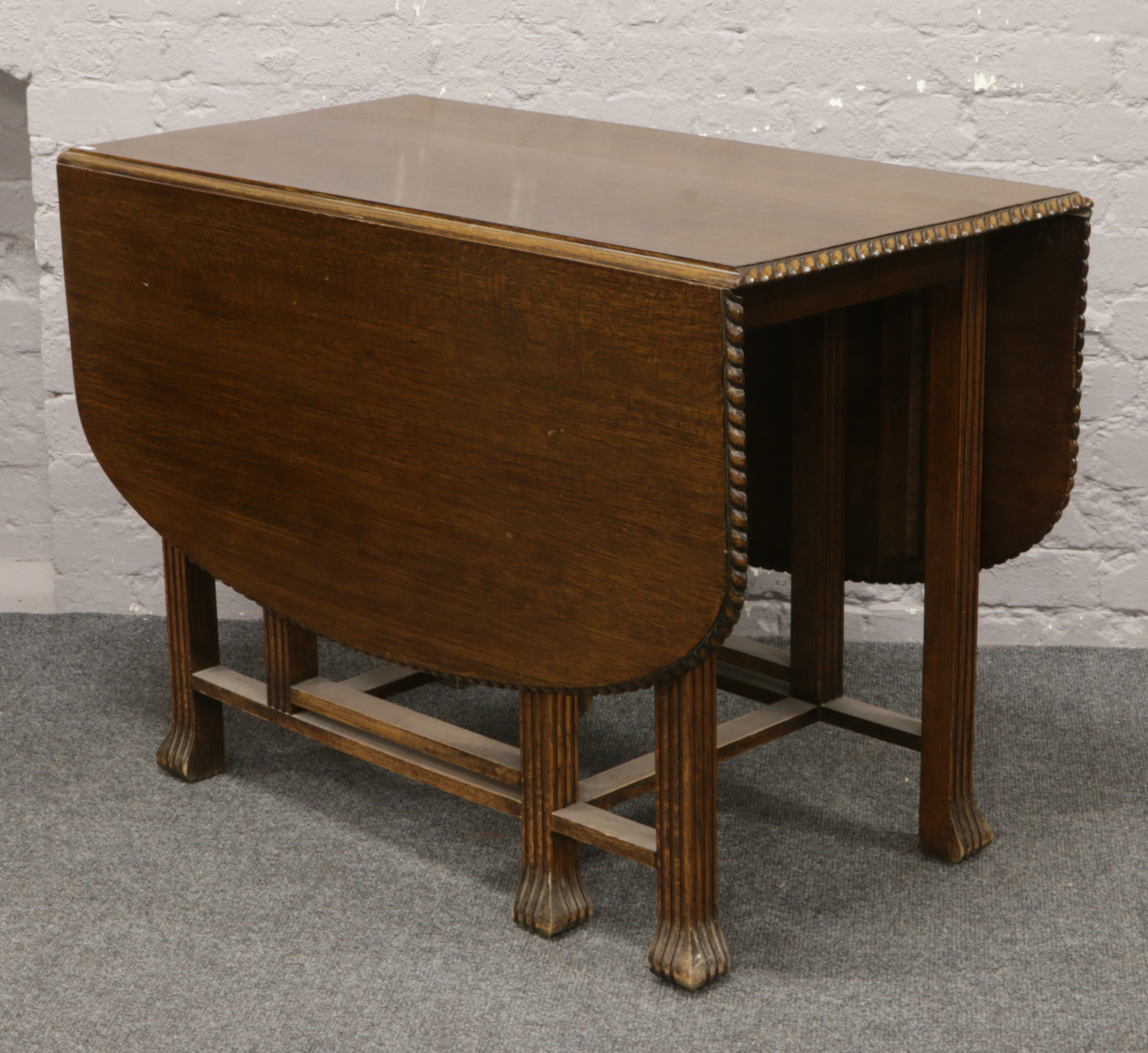 A carved oak drop leaf table raised on reeded supports.