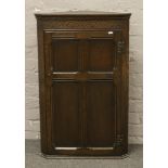 A carved and panelled oak corner cupboard. (Height 91.5cm, Width 52cm)