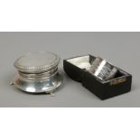 A silver ring box raised on paw feet assayed Birmingham 1924 and a cased silver serviette ring,