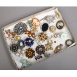 A tray of costume brooches to include white and coloured paste stone examples etc.
