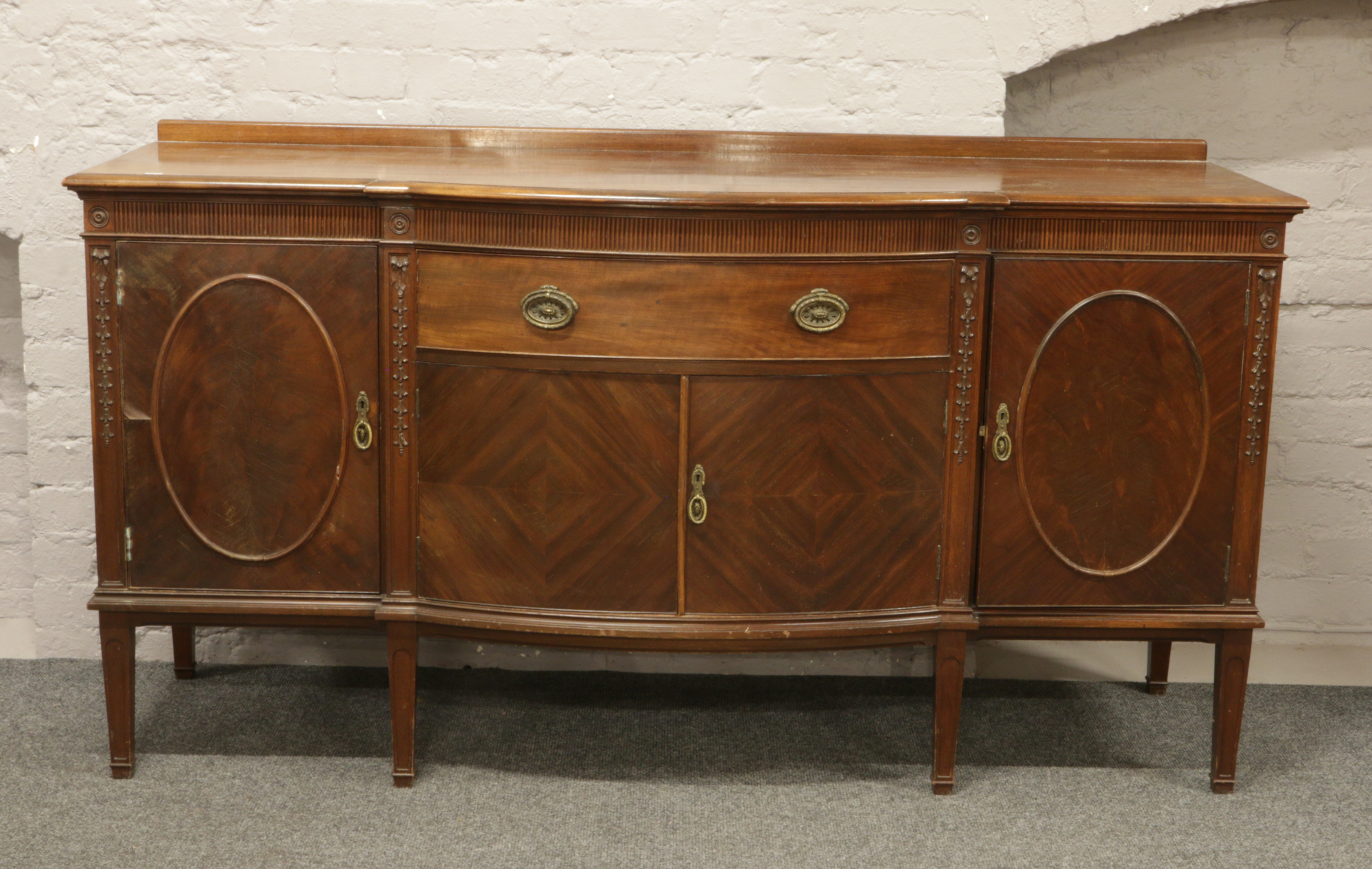 A George V carved mahogany breakfront sideboard raised on square tapering legs, H 98cm x L 181cm x D